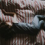 kid sleeping on red and gray bed